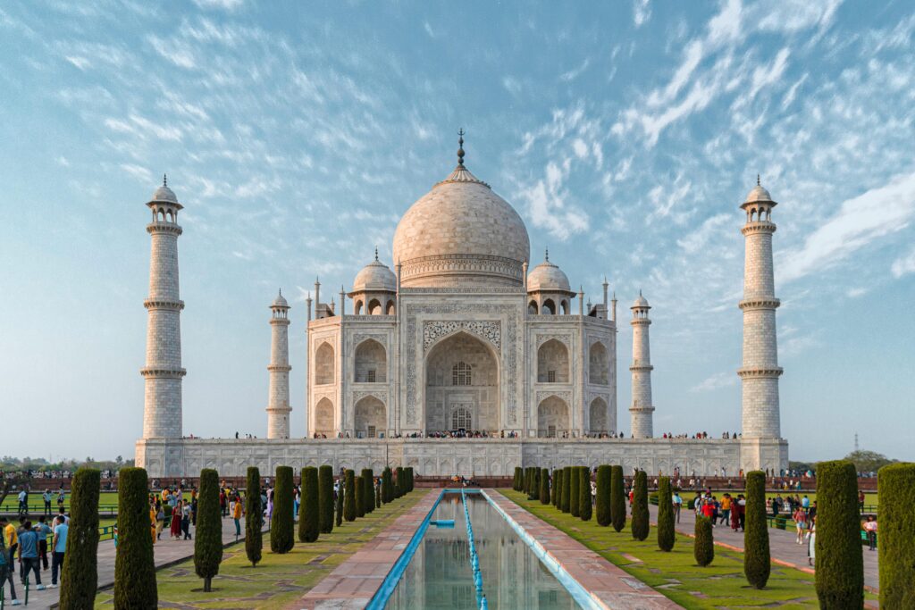 Front view of the Taj Mahal, showcasing its iconic architecture against a blue sky.
