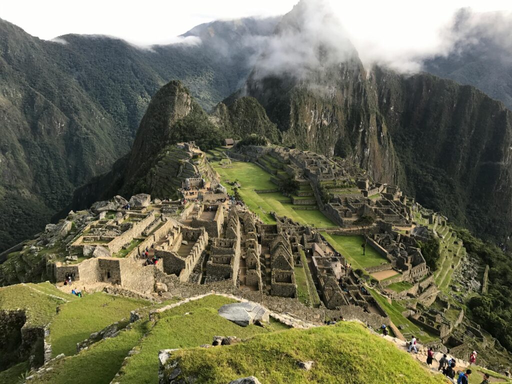 Stunning aerial view of Machu Picchu with lush mountains and clouds in the background.
